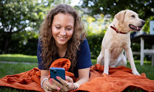 En tjej med en mobiltelefon och en hund